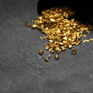 A pouch with scattered gold nugget grains, on cement background
